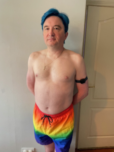 Me in Pride swimming trunks, looking into the camera